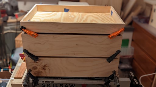 A stack of drawers, which are glued up and clamped, waiting to get installed