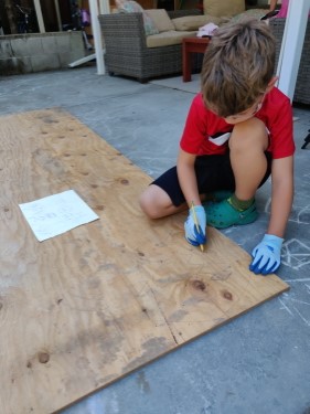 Kid transferring his sketches onto a sheet of plywood